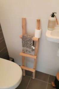 houten ladder in toilet met wc rol en handdoek