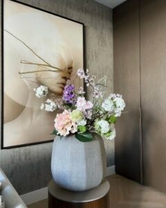 Graue hohe Vase mit weißen Kunstblumen